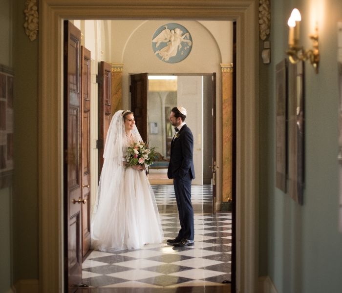 A bride and groom smile while talking in the Grand Entrance of Hylands House. 