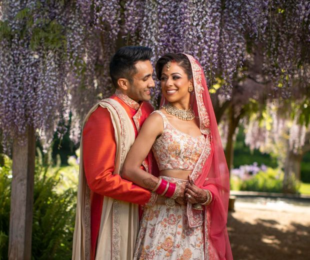 A groom embracing his bride under the wisteria. 
