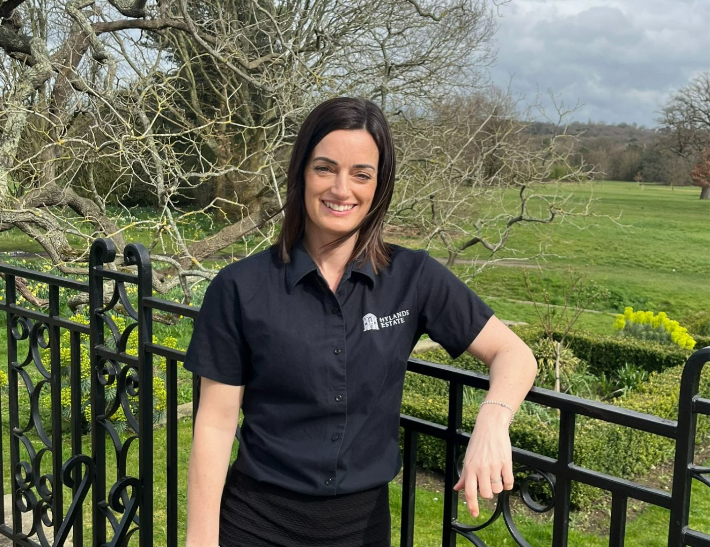 Jemma, a woman with shoulder-length dark hair, smiling while standing on the East Terrace. 