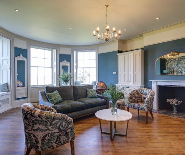 The Repton Room inside Hylands House with a seating area and windows looking over Hylands parkland. 