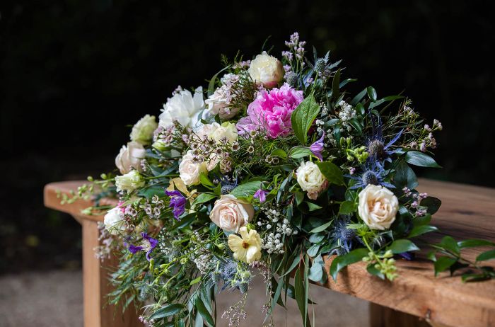 Close up of a floral bouquet on an outdoor wooden seat. 