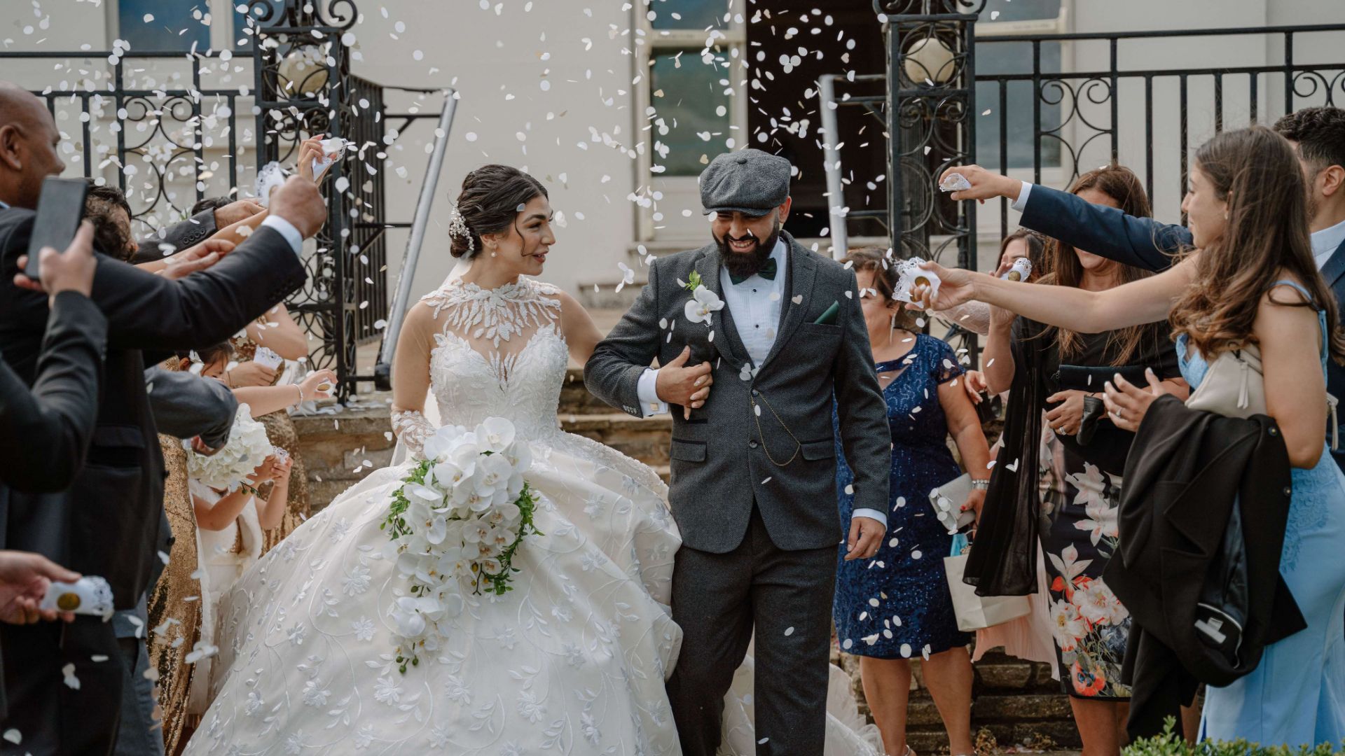 Wedding guests throwing floral confetti at the couple. 