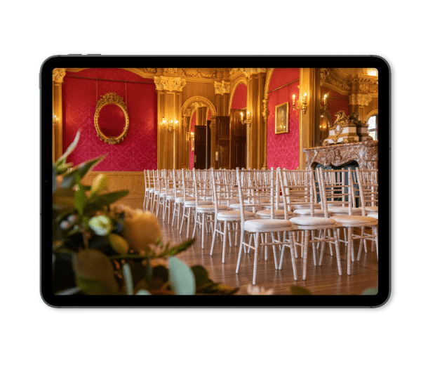 A tablet showing a photo of the Braqueting Room set for a wedding ceremony. 