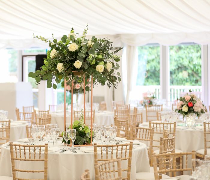 Tables in the Grand Pavilion set for dinner with floral centrepieces. 