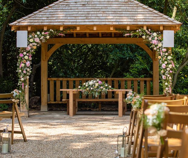 The gazebo of the Outdoor Ceremony Garden decorated with pink and white flowers. 