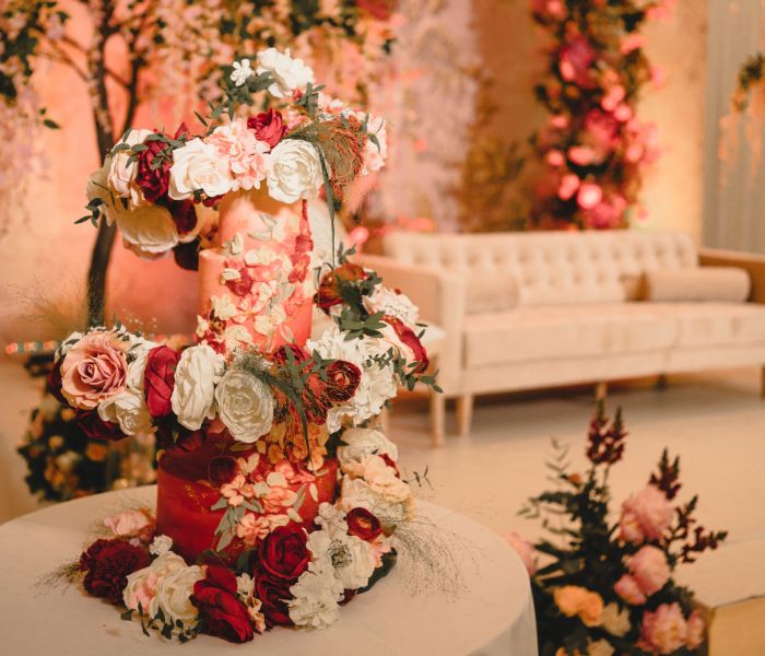 A multi-tiered pink and red wedding cake with roses adorning it. 