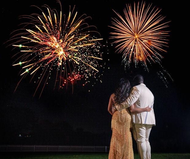 A bride and groom looking out at a firework display. 