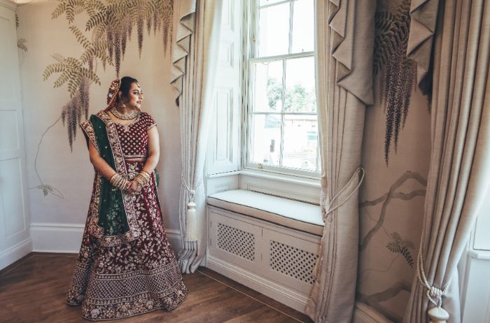 A bride looks out the window of the Wisteria Suite. 