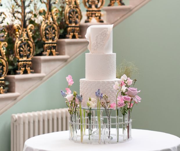 A white tiered cake surrounded by spring florals.
