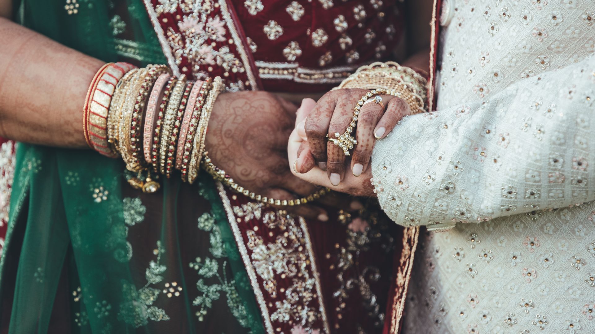 A close up of a couple with Henna holding hands. 