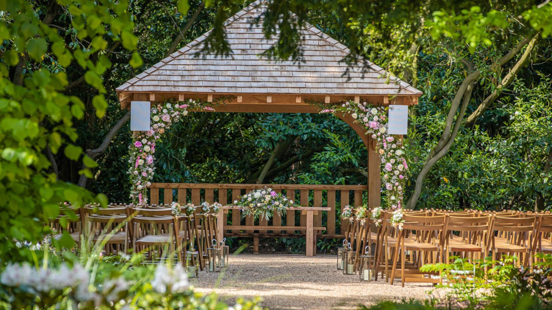 The gazebo of the Outdoor Ceremony Garden decorated with pink and white flowers. 