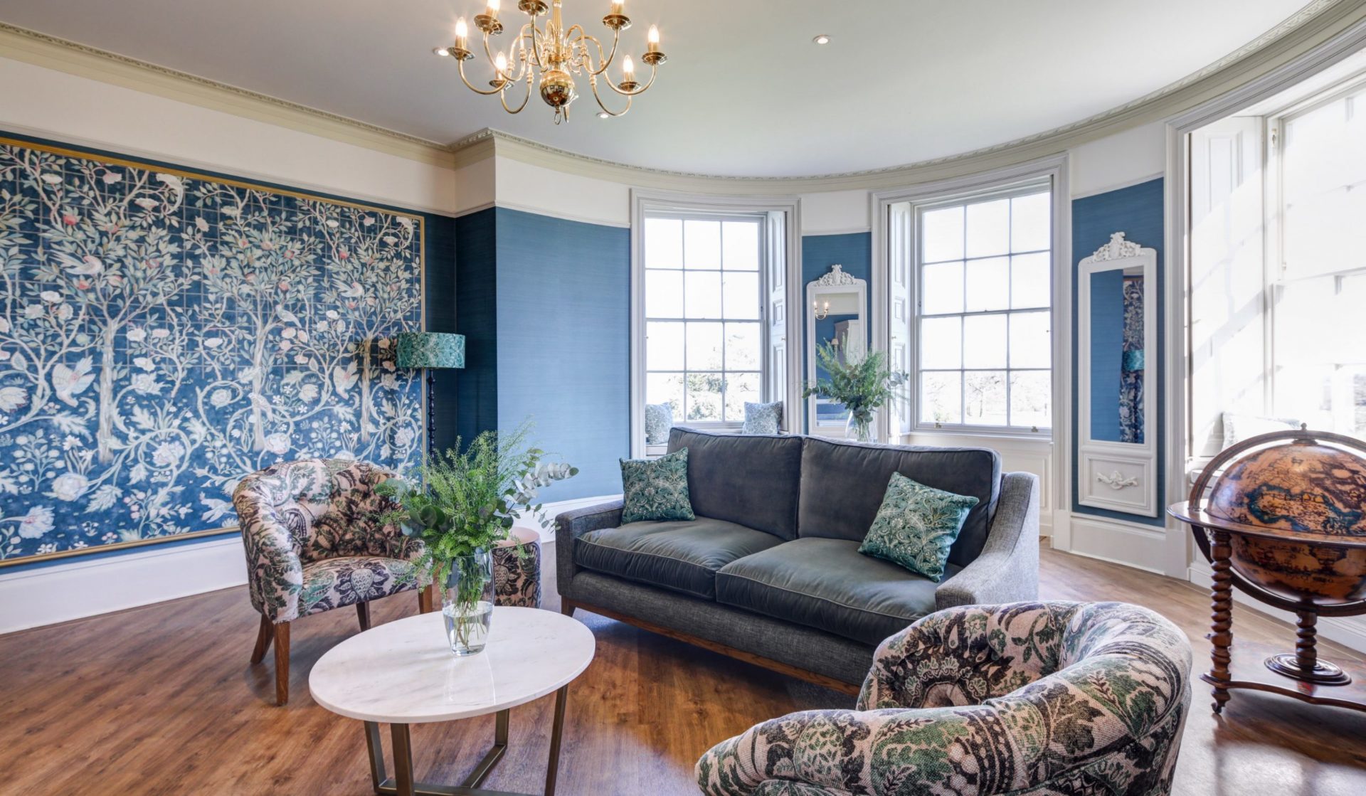 The Repton Room inside Hylands House with a seating area and a navy floral accent wall. 
