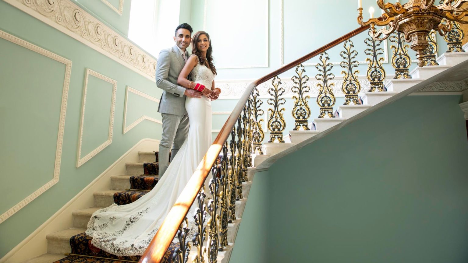 A bride and groom embracing on the Grand Staircase of Hylands House. 
