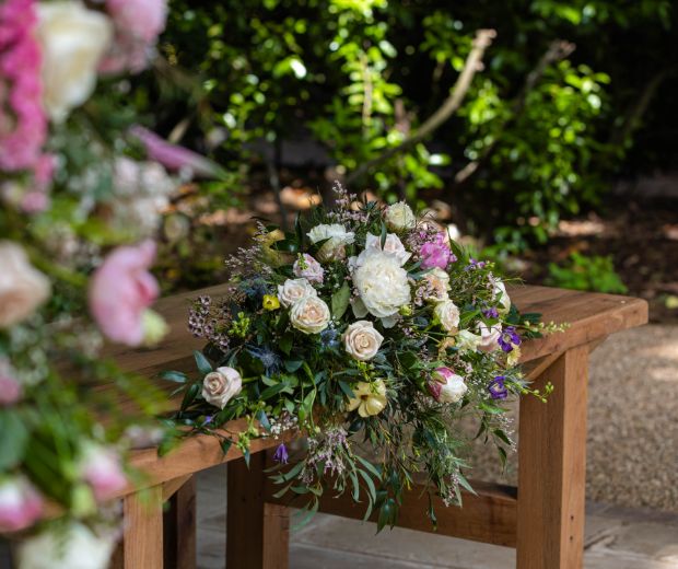 Close up of a floral bouquet on an outdoor wooden seat. 