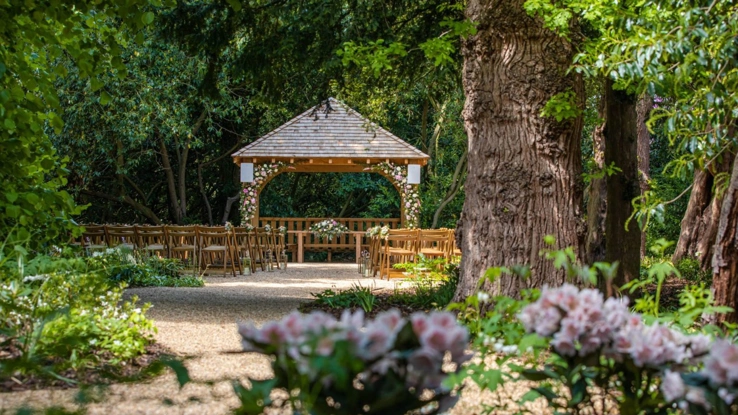 The outdoor ceremony garden with pink flowers decorating the gazebo. 