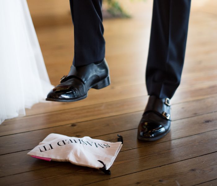 A close up of a man about to step on a bag with 'smashed it' embroidered on it. 