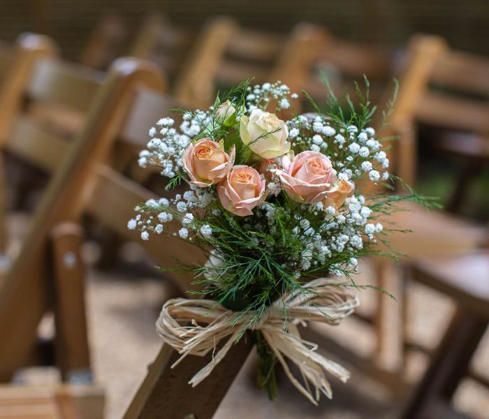 Close up of a floral bouquet on an outdoor wooden seat. 