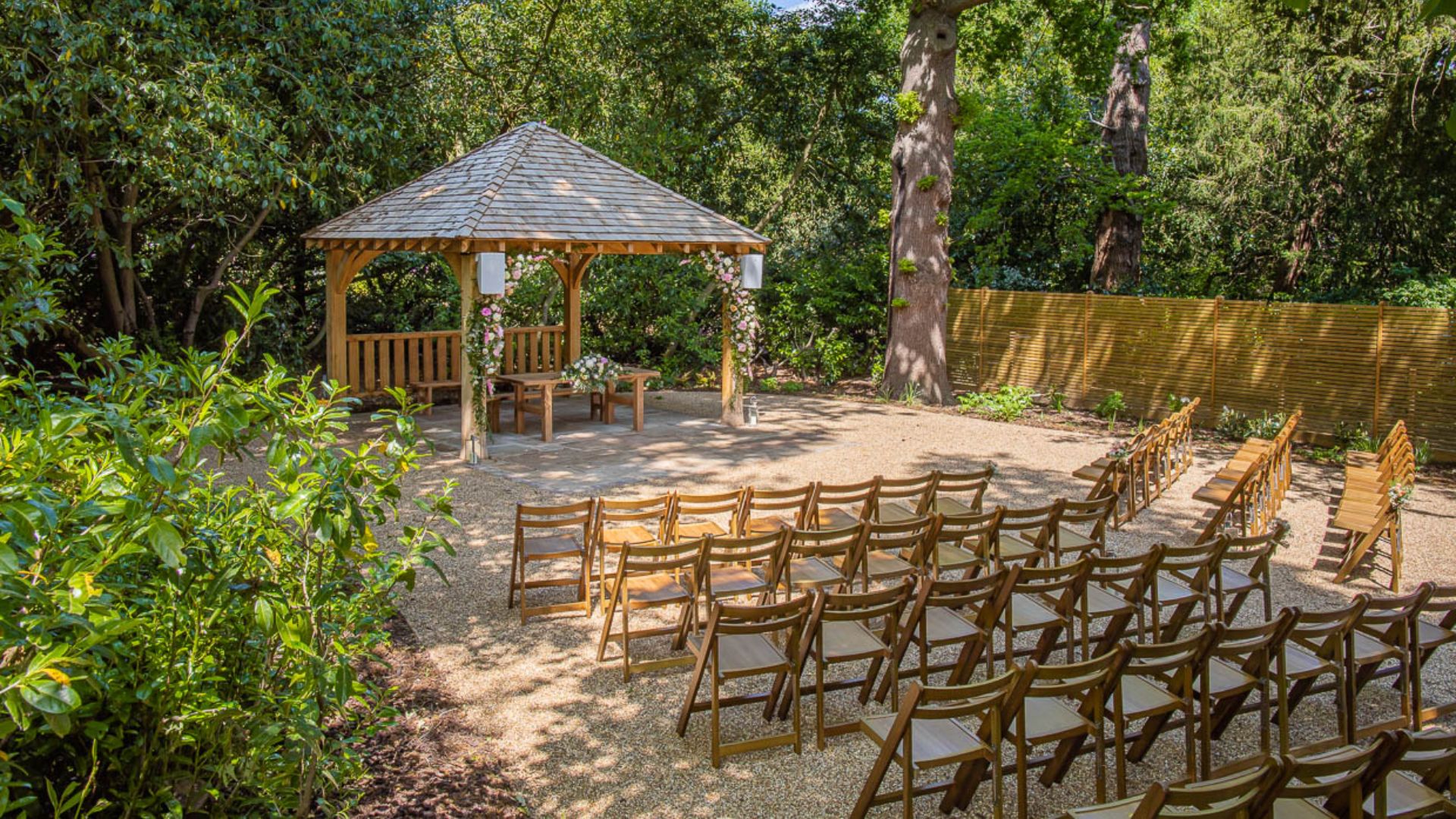 The gazebo of the Outdoor Ceremony Garden decorated with pink and white flowers. 